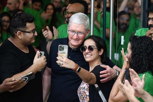 Chief Executive Officer of Apple Tim Cook (C) poses for a selfie with a woman during the opening of Apple's first retail store in India, in Mumbai on April 18, 2023. Apple opened its first retail store in India on April 18, underscoring the US tech titan's increasing focus on the South Asian nation as a key sales market and alternative manufacturing hub to China. (Photo by Punit Paranjpe/AFP Photo)