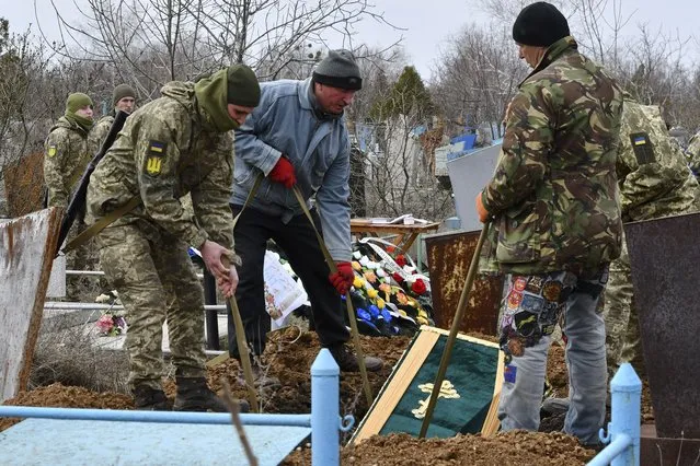 Ukrainian servicemen lower the coffin of their comrade Anatoly German during a funeral ceremony in Kramatorsk, Ukraine, Tuesday, April 5, 2022. Anatoly German was killed during fightings between Russian and Ukrainian forces near the city of Severodonetsk. He leaves a wife, daughter Adelina, 9, son Kirill, 3. (Photo by Andriy Andriyenko/AP Photo)