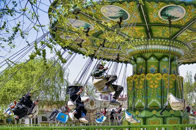People enjoy a ride on a carousel at an amusement park in Kabul on March 28, 2022. (Photo by Ahmad Sahel Arman/AFP Photo)