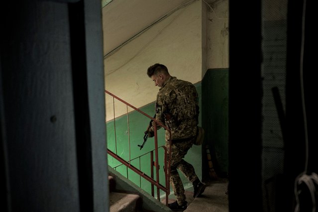 A Ukrainian serviceman walks inside a building after searching the apartment of a man suspected of being a Russian collaborator in Kharkiv, Ukraine, Saturday, April 23, 2022. (Photo by Felipe Dana/AP Photo)