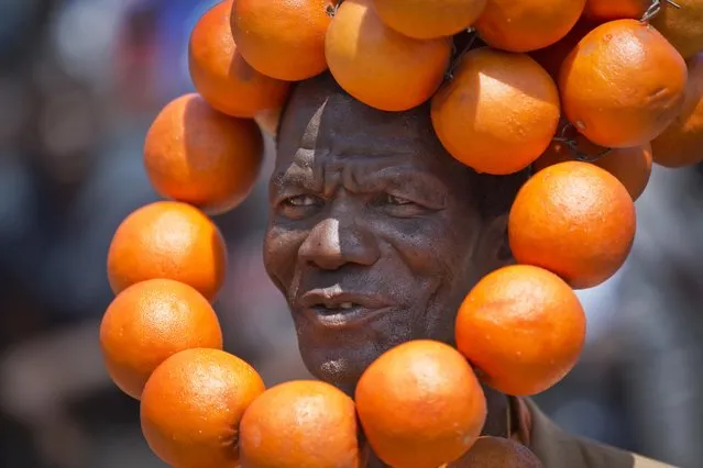 An opposition supporter wears a headdress of plastic oranges, the party color, as he and others attend a rally of opposition leader Raila Odinga to commemorate Madaraka Day, when Kenya attained internal self-rule in 1963, at Uhuru Park in Nairobi, Kenya, Wednesday, June 1, 2016. The government and opposition held opposing celebrations Wednesday, following weeks of opposition protests demanding the electoral commission be dissolved ahead of next year's elections, due to allegations of bias and corruption. (Photo by Ben Curtis/AP Photo)