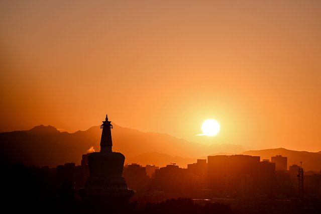 The sun sets against the White Dagoba or Bai Ta, as seen from the Jingshan hill in Beijing on August 27, 2024. (Photo by Adek Berry/AFP Photo)