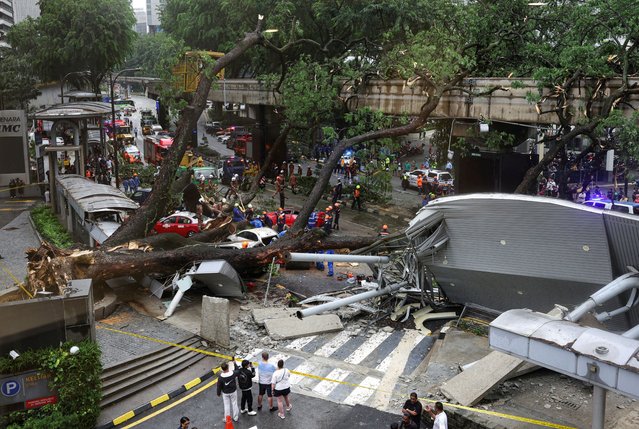 A view of rescuers working where a tree fell across Jalan Sultan Ismail, one of Kuala Lumpur's busiest roads smashing 17 cars and disrupting monorail service, seen through a window, in Kuala Lumpur, Malaysia on May 7, 2024. (Photo by Hasnoor Hussain/Reuters)