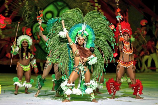 Artists of Garantido Cultural Association perform during the annual folklore festival known as Boi Bumba at Bumbodromo, in Parintins, an island on the Amazon river about 370km east of Manaus, northern Brazil, on June 30, 2023. Boi Bumba is considered the biggest outdoor opera, which is performed by two competing sides, the Garantido (in Red) and Caprichoso (in Blue), for three nights on the last weekend of June. The themes, costumes, and songs are based on the native cultures along the Amazon River. The float can be over 30 meters high. (Photo by Michael Dantas/AFP Photo)