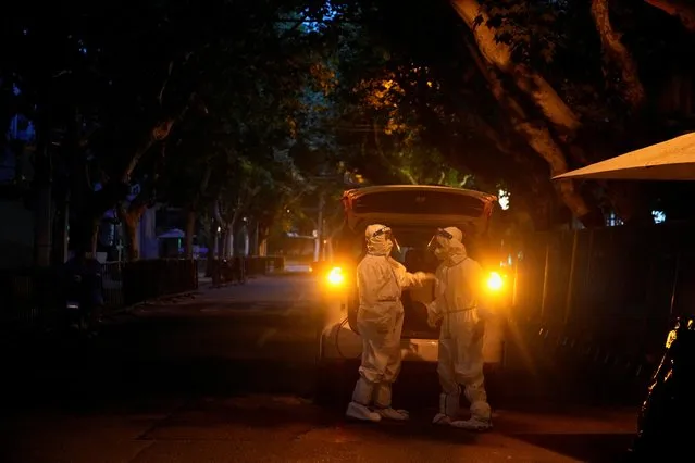 Workers in protective suits stand in a closed street during lockdown, amid the coronavirus disease (COVID-19) pandemic, in Shanghai, China, May 19, 2022. (Photo by Aly Song/Reuters)