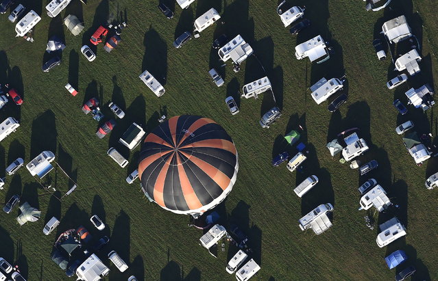 A balloon flies over a camping site in Bristol during a mass launch at the Bristol International Balloon Fiesta in south west England August 7, 2015. (Photo by Toby Melville/Reuters)