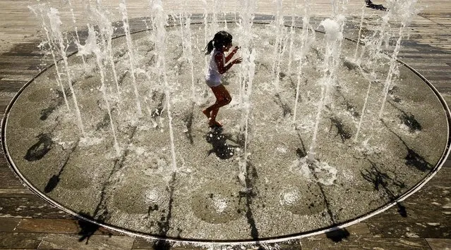 A girl refreshes under a fountain during hot temperatures on Sechselaeutenplatz square in Zurich, August 3, 2015. (Photo by Arnd Wiegmann/Reuters)