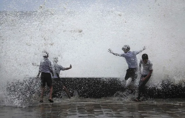 School boys get drenched in a large wave during high tide at a sea front in Mumbai July 14, 2014. Weak rainfall in India since the start June, when the monsoon season began, has raised concerns of a first drought in five years, although weather experts are hopeful rains will revive in the next week. (Photo by Danish Siddiqui/Reuters)