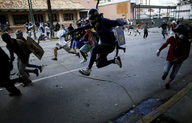 Anti-government protesters run from advancing Venezuelan Bolivarian National Guard officers on the first day of a 48-hour general strike in protest of government plans to rewrite the constitution, in Caracas, Venezuela, Wednesday, July 26, 2017. President Nicolas Maduro is promoting the constitution rewrite as a means of resolving Venezuela's political standoff and economic crisis, but opposition leaders are boycotting it. (Photo by Ariana Cubillos/AP Photo)