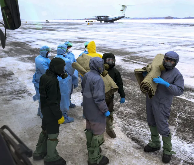 A group of medical personnel stands ready to control 80 people, accompanied by medical specialists, carried by a Russian military plane at an airport outside Tyumen, Russia, Wednesday, February 5, 2020. Russia has evacuated 144 people – Russians and nationals of Belarus, Ukraine and Armenia – from the epicenter of the coronavirus outbreak in Wuhan, China, on Wednesday. All evacuees will be quarantined for two weeks in a sanatorium in the Tyumen region in western Siberia, government officials said. (Photo by Maxim Slutsky/AP Photo)