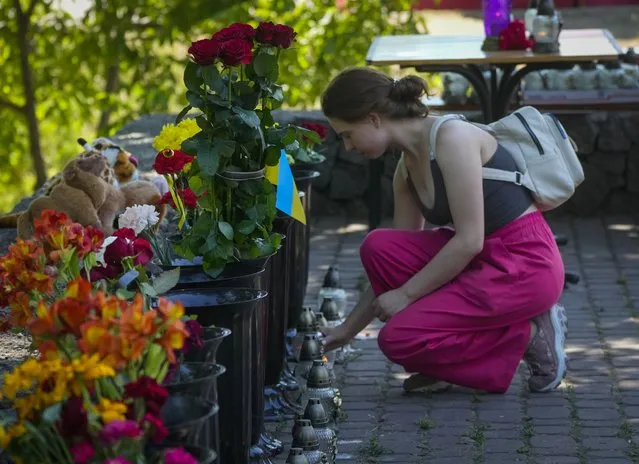 A woman lights a candle at a shopping center, after a rocket attack in Kremenchuk, Ukraine, Tuesday, June 28, 2022. (Photo by Efrem Lukatsky/AP Photo)