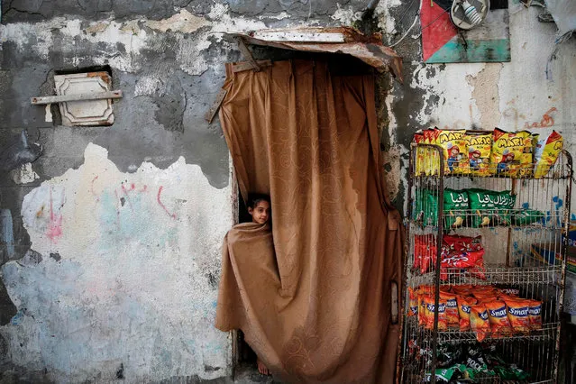 A Palestinian girl stands behind a curtain through the doorway of a house past a rack of potato chips (crisps) at al-Shati camp for Palestinian Refugees in Gaza City on January 28, 2020. (Photo by Mohammed Abed/AFP Photo)