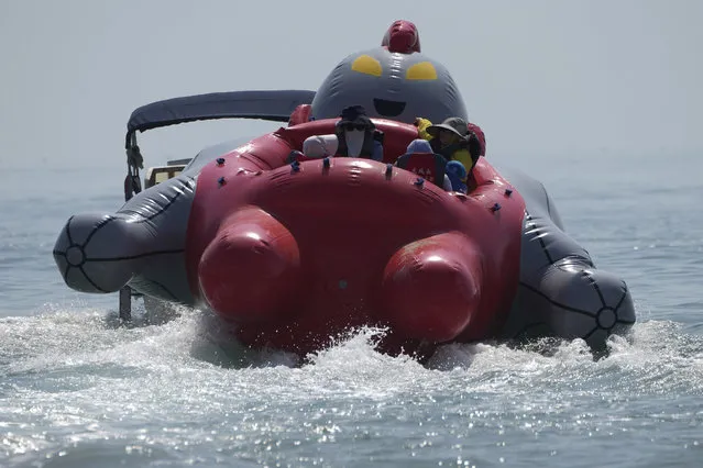Tourists take a ride on an inflated Ultraman raft from a beach along the Taiwan Strait in Pingtan, eastern China's Fujian Province, Sunday, August 7, 2022. (Photo by Ng Han Guan/AP Photo)
