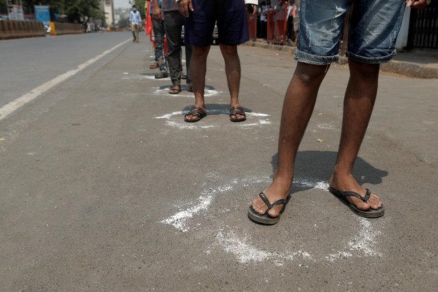 People line up in circles drawn with chalk to maintain safe distance as they wait to enter a supermarket during the coronavirus disease (COVID-19) outbreak in Mumbai, India, March 25, 2020. (Photo by Francis Mascarenhas/Reuters)