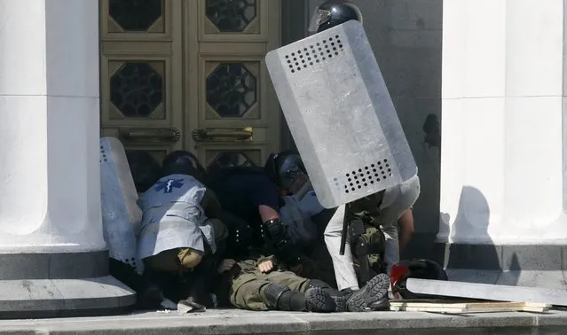 An injured serviceman lies outside the parliament building in Kiev, Ukraine, August 31, 2015. Several police and members of the Ukrainian national guard were injured on Monday when a grenade was thrown from a crowd of nationalist protesters demonstrating outside parliament in Kiev against a draft law to give special status to separatist regions, police said. (Photo by Valentyn Ogirenko/Reuters)