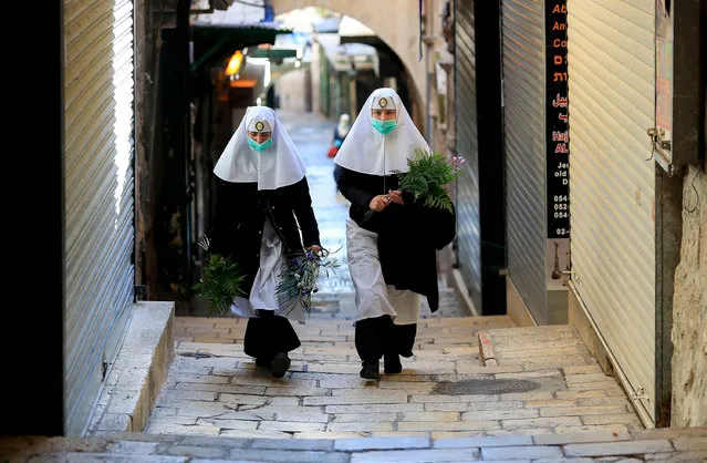 Nuns walk along the Via Dolorosa (Way of Sorrow), ahead of Easter Sunday service amid the coronavirus disease (COVID-19) outbreak, in Jerusalem's Old City on April 12, 2020. All cultural sites in the Holy Land are shuttered, regardless of their religious affiliation, as authorities seek to forestall the spread of the deadly respiratory disease. Christians will be prevented from congregating for the Easter service, whether this coming Sunday – as in the case of Bitar and fellow Catholics – or a week later on April 19 in the case of the Orthodox. (Photo by Emmanuel Dunand/AFP Photo)