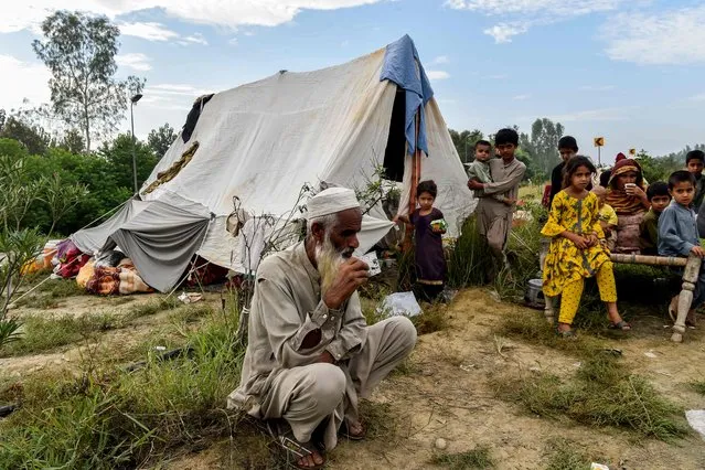 Displaced people take refuge along a highway after fleeing from their flood hit homes following heavy monsoon rains in Charsadda district in the Khyber Pakhtunkhwa province of Pakistan on August 27, 2022. (Photo by Abdul Majeed/AFP Photo)