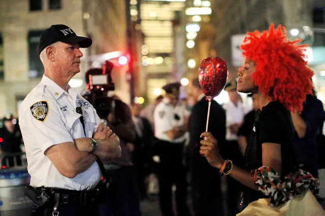 A woman holds a balloon toward a police officer during a Black Lives Matters protest outside City Hall in Manhattan, New York, U.S., August 1, 2016. (Photo by Andrew Kelly/Reuters)