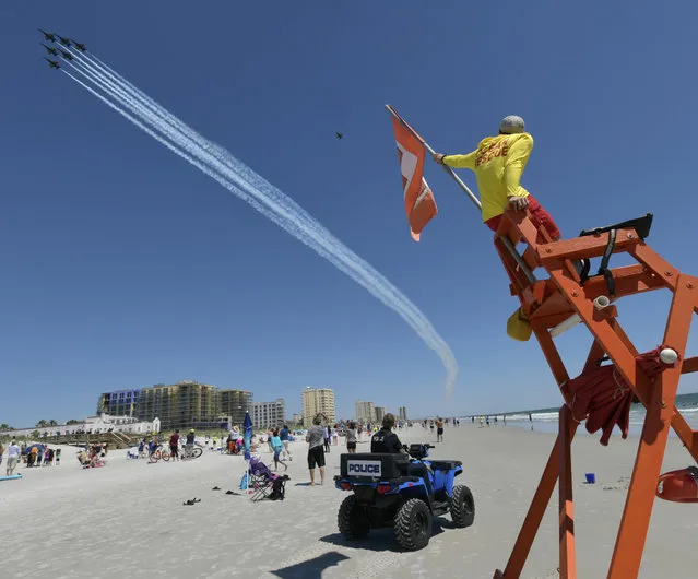 The U.S Navy's Blue Angels fly over as Jacksonville Beach Police Officer Thomas Harper and lifeguard Josh Mullis look on Friday, May 8, 2020 in Jacksonville Beach, Fla. The flyover was a salute to first responders in the wake of the coronavirus pandemic. (Photo by Will Dickey/The Florida Times-Union via AP Photo)