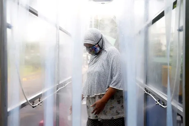 A woman wearing a protective face mask stands in a disinfection chamber before receiving rice from an automated rice ATM distributor amid the spread of the coronavirus disease (COVID-19) in Jakarta, Indonesia on May 4, 2020. (Photo by Ajeng Dinar Ulfiana/Reuters)