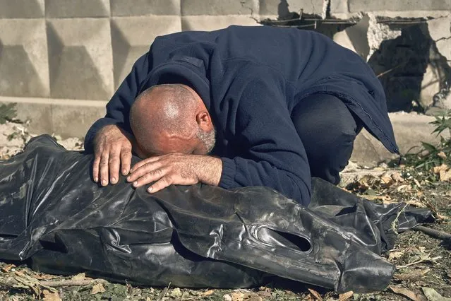A man reacts near the body of his cousin, killed in a Russian rocket attack in Mykolaiv, Ukraine, Thursday, October 13, 2022. (Photo by LIBKOS/AP Photo)