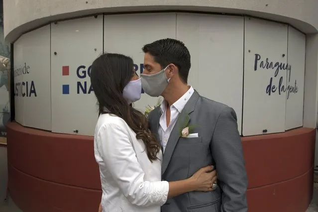 Bride Loris Sanchez and groom Manuel Soria, wearing protective face masks as a precaution against the spread of the new coronavirus, share a kiss before during their wedding ceremony at the Civil Registry office, in Asuncion, Paraguay, Saturday, June 13, 2020. The government has eased restrictive quarantine measures due to the COVID-19 pandemic, authorizing the opening of some stores, restaurants and government offices that had been closed since March 10, as part of a plan coined, “Intelligent Quarantine”. (Photo by Jorge Saenz/AP Photo)