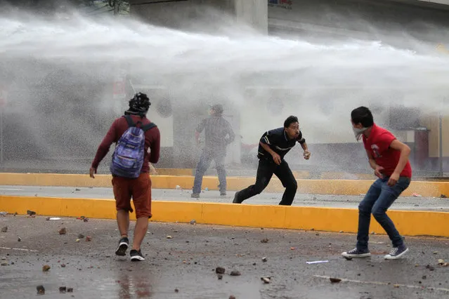 Supporters of Salvador Nasralla, presidential candidate for the Opposition Alliance Against the Dictatorship, avoid water fired from a police water cannon during a protest while waiting for official presidential election results in Tegucigalpa, Honduras November 30, 2017. (Photo by Jorge Cabrera/Reuters)