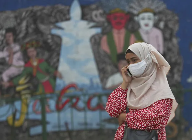 A women wears a face mask to help curb the spread of the coronavirus as she talks on her phone in Jakarta Monday, July 20, 2020. The number of coronavirus cases in Indonesia surpassed 50,000 in June, an increase that is worrying experts at a time when the government is allowing businesses to reopen amid increasing economic pressure. (Photo by Achmad Ibrahim/AP Photo)