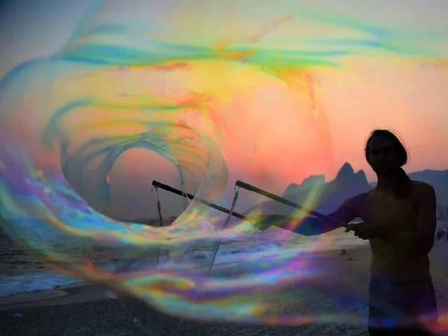 German tourist Florian plays with bubbles at sunset, in Ipanema beach in Rio de Janeiro on October 13, 2014. (Photo by Christophe Simon/AFP Photo)