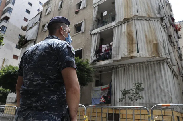 In this Saturday, May 23, 2020 photo, a Lebanese policeman is deployed to enforce isolation outside a building where dozens of foreign workers living in overcrowded apartments have tested positive with the coronavirus, in Beirut, Lebanon. Some 250,000 registered migrant laborers in Lebanon – maids, garbage collectors, farm hands and construction workers – are growing more desperate as a crippling economic and financial crisis sets in, coupled with coronavirus restrictions. With no functioning airports and exorbitant costs of repatriation flights, many are trapped, unable to go home. (Photo by Hussein Malla/AP Photo)