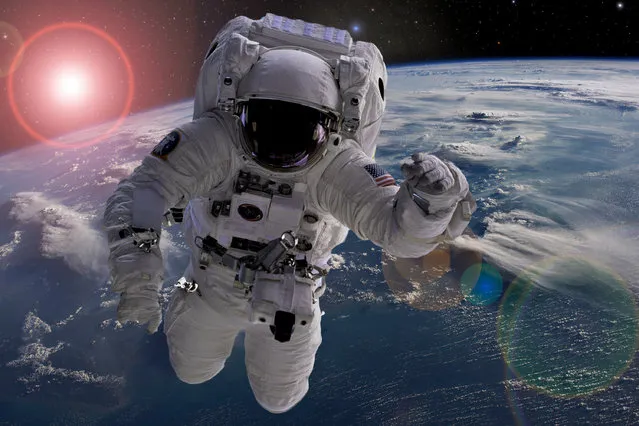 Astronaut flying in outer space near planet earth doing some work near space ship. (Photo by Mike_shots/Shutterstock)