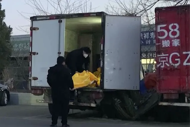 Workers load body bags into a truck at a funeral complex in Beijing, Friday, December 16, 2022. Deaths linked to COVID are beginning to appear in China, even as those deaths are not reflected in the official tally. Relatives of people who died in Beijing said their loved ones had tested positive for the coronavirus before their deaths, while employees at shops in one funeral complex said there has been a noticeable uptick in traffic in the past few days. (Photo by Dake Kang/AP Photo)
