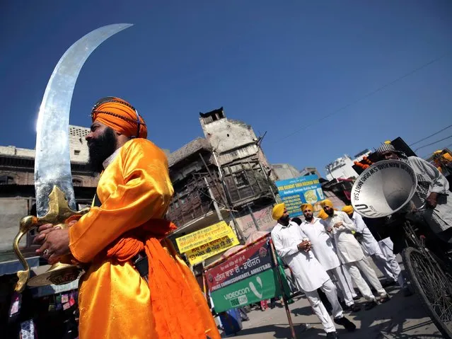 A Sikh devotee carries on over-sized religious sword during a religious procession to celebrate the birth anniversary of the first Sikh Guru or master, Sri Guru Nanak Dev Ji, the founder of Sikhism in Amritsar, India, 05 November 2014. The birth anniversary of Guru Nanak Dev Ji will be observed on 06 November. (Photo by Raminder Pal Singh/EPA)