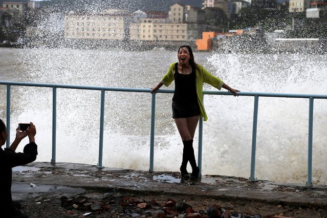 A woman poses for pictures in front of tidal waves under the influence of typhoon Meranti in Wenling, Zhejiang province, China, September 16, 2016. (Photo by Reuters/Stringer)