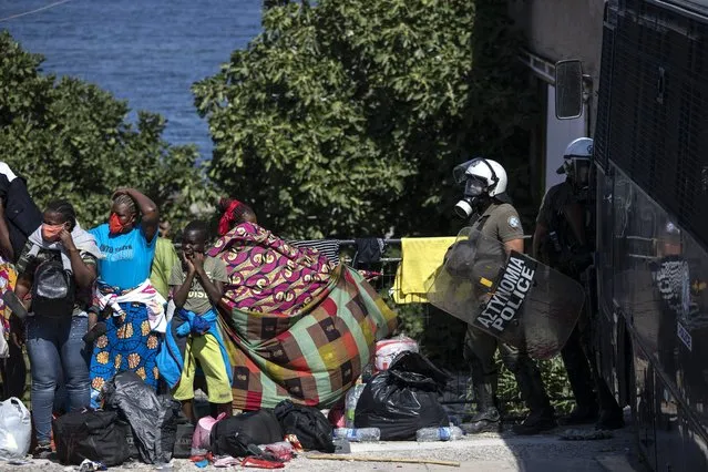Migrants take part in a rally as riot police block the road near Mytilene town, on the northeastern island of Lesbos, Greece, Friday, September 11, 2020. Thousands of protesting refugees and migrants left homeless on the Greek island of Lesbos after fires destroyed the notoriously overcrowded Moria camp have gathered on a road leading to the island's main town, demanding to be allowed to leave. (Photo by Petros Giannakouris/AP Photo)