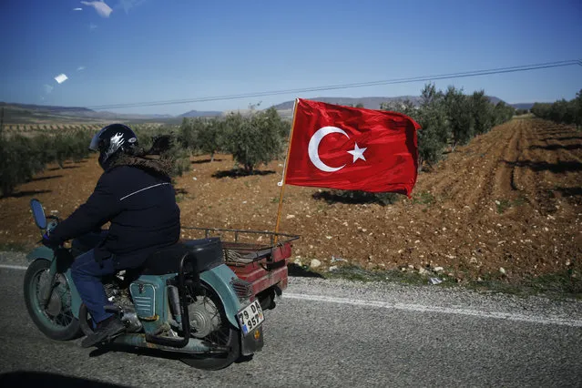 A Turkish motorcyclist drives on the outskirts of the border town of Kilis, Turkey, in support of Turkish troops, Tuesday, January 30, 2018. Turkey launched a military offensive against Afrin on Jan. 20 to drive out the Syrian Kurdish People's Protection Units, or YPG, which is says are an extension of the outlawed Kurdish rebels inside Turkey. (Photo by Lefteris Pitarakis/AP Photo)