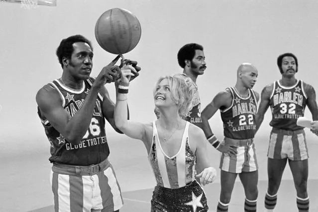 Actress Goldie Hawn has her finger guided to the basketball by Harlem Globetrotters' Meadowlark Lemon, during the taping of her CBS special in Burbank, Calif., February 2, 1978. In the background are teammates Curley Neal and Robert Paige, other player is unidentified. (Photo by Jeff Robbins/AP Photo)