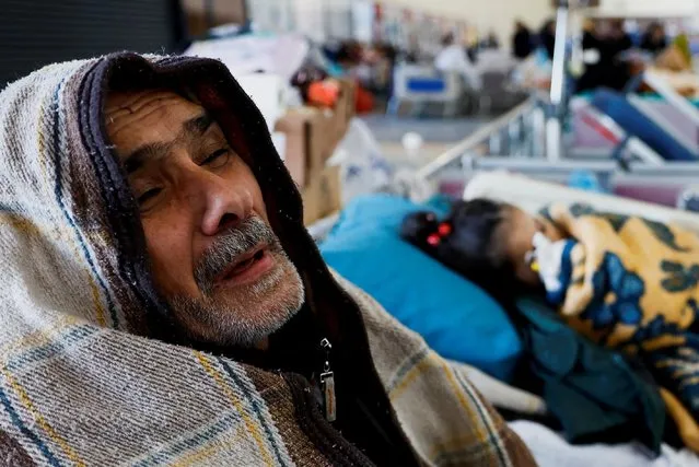 A man reacts as he sits next to a child lying in a bed at a hospital, in the aftermath of an earthquake, in Kahramanmaras, Turkey on February 7, 2023. (Photo by Suhaib Salem/Reuters)