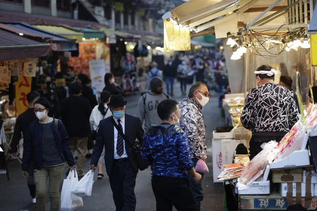 A shopper, second right, wearing a face mask buys sea food at a shopping street in Tokyo on Thursday, November 19, 2020. Japan's number of reported coronavirus infections hit a record high Thursday, and the prime minister urged maximum caution but stopped short of calling for restrictions on travel or business. (Photo by Hiro Komae/AP Photo)