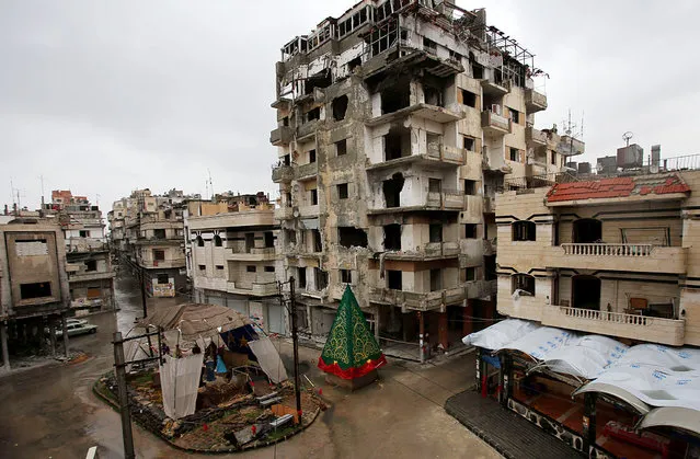 A crib made out of rubble and a Christmas tree are set on a roundabout in the regime-held Hamedieh neighborhood in the Syrian city of Homs on December 22, 2014, as Christians around the world prepare to celebrate the holy day. (Photo by Youssef Karwashan/AFP Photo)