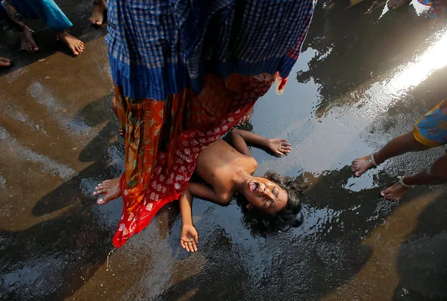 A child reacts as a Hindu woman steps over him in a ritual seeking blessings for the child from the Sheetala Mata, the Hindu goddess of smallpox, during Sheetala Puja in which devotees pray for betterment of their family and society, in Kolkata, India, April 14, 2018. (Photo by Rupak De Chowdhuri/Reuters)