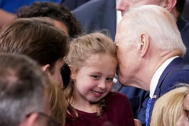 U.S. President Joe Biden whispers in the ear of a young girl as he greets workers and their families during his visit to the Cummins Power Generation Facility in Fridley, Minnesota, U.S., April 3, 2023. (Photo by Kevin Lamarque/Reuters)