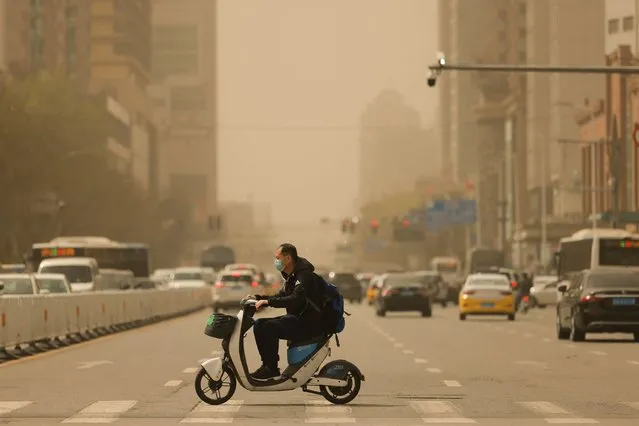 A man rides a scooter on a street during a sandstorm in Shenyang, in China's northeastern Liaoning province on April 11, 2023. (Photo by AFP Photo/China Stringer Network)