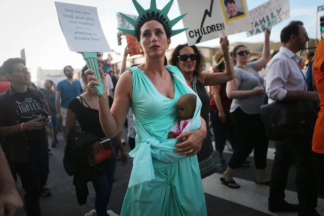 A protestor dressed as Lady Liberty carries a doll, depicting a baby of color, as demonstrators march at the “Families Belong Together March” against the separation of children of immigrants from their families on June 14, 2018 in Los Angeles, California. Demonstrators marched through the city and culminated the march at a detention center where ICE (U.S.Immigration and Customs Enforcement) detainees are held. U.S. Immigration and Customs Enforcement recently arrested 162 undocumented immigrants during a three-day operation in Los Angeles and surrounding areas. (Photo by Mario Tama/Getty Images)