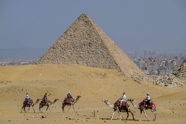 Tourists ride camels at the Giza Pyramids necropolis on the outskirts of the twin city of Egypt's capital on November 7, 2025. (Photo by Khaled Desouki/AFP Photo)