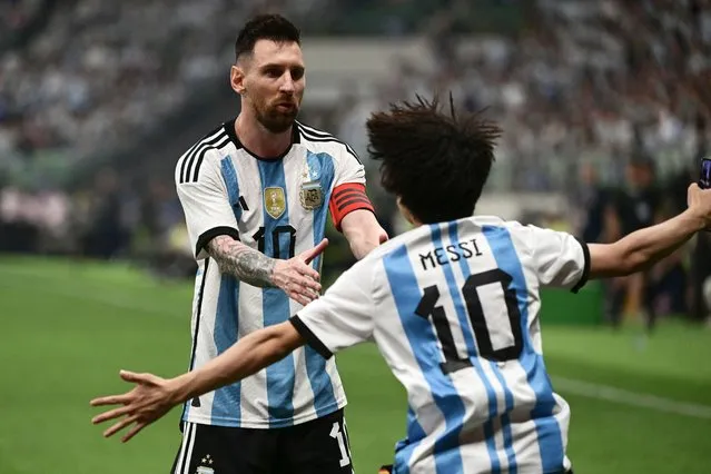 A fan (R) runs towards Argentina's Lionel Messi during a friendly football match between Australia and Argentina at the Workers' Stadium in Beijing on June 15, 2023. (Photo by Pedro Pardo/AFP Photo)