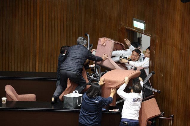 Lawmakers from the main opposition Kuomintang (KMT) (in white) try to break into Parliament where Democratic Progressive Party (DPP) occupied the night to avoid the passing of the third reading of amendments to the Civil Servants Election and Recall Act and other controversial bills at the Legislative Yuan in Taipei on December 20, 2024. (Photo by I-Hwa Cheng/AFP Photo)