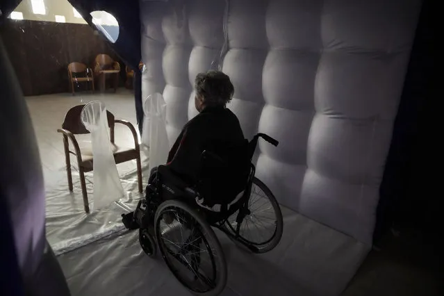 Caterina Salvi, 90, waits visits inside a protective inflatable plastic tunnel at the Martino Zanchi nursing home in Alzano Lombardo, northern Italy, Wednesday, February 24, 2021. The protective tunnel was set up to allow home residents to have personal contact with their families and still stay safe respecting the anti-COVID-19 precautions. (Photo by Luca Bruno/AP Photo)
