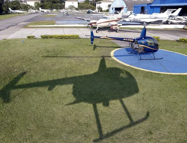 A Robson 44 helicopter casts a shadow as it prepares to land at Campo de Marte airport in Sao Paulo April 12, 2015. (Photo by Paulo Whitaker/Reuters)