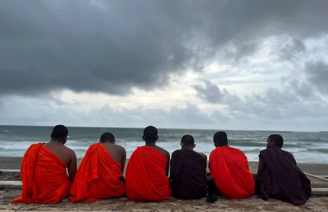 Buddhist monks sit at a beach as rainy clouds gather above during the monsoon season, in Colombo, Sri Lanka on May 11, 2023. (Photo by Dinuka Liyanawatte/Reuters)